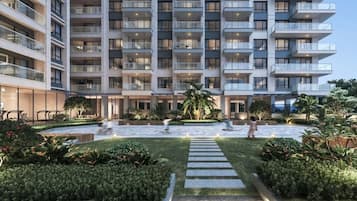 Un hotel de varios pisos con balcones, un patio central con fuente de agua y jardines bien cuidados.