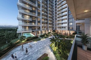 Un edificio residencial alto con varios balcones, una piscina y jardines ajardinados.