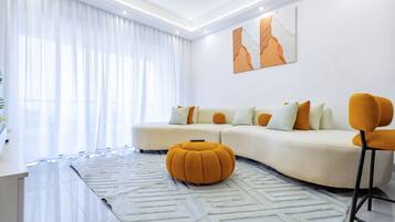 Una sala de estar moderna con un sofá, un reposapiés y un taburete de bar.
