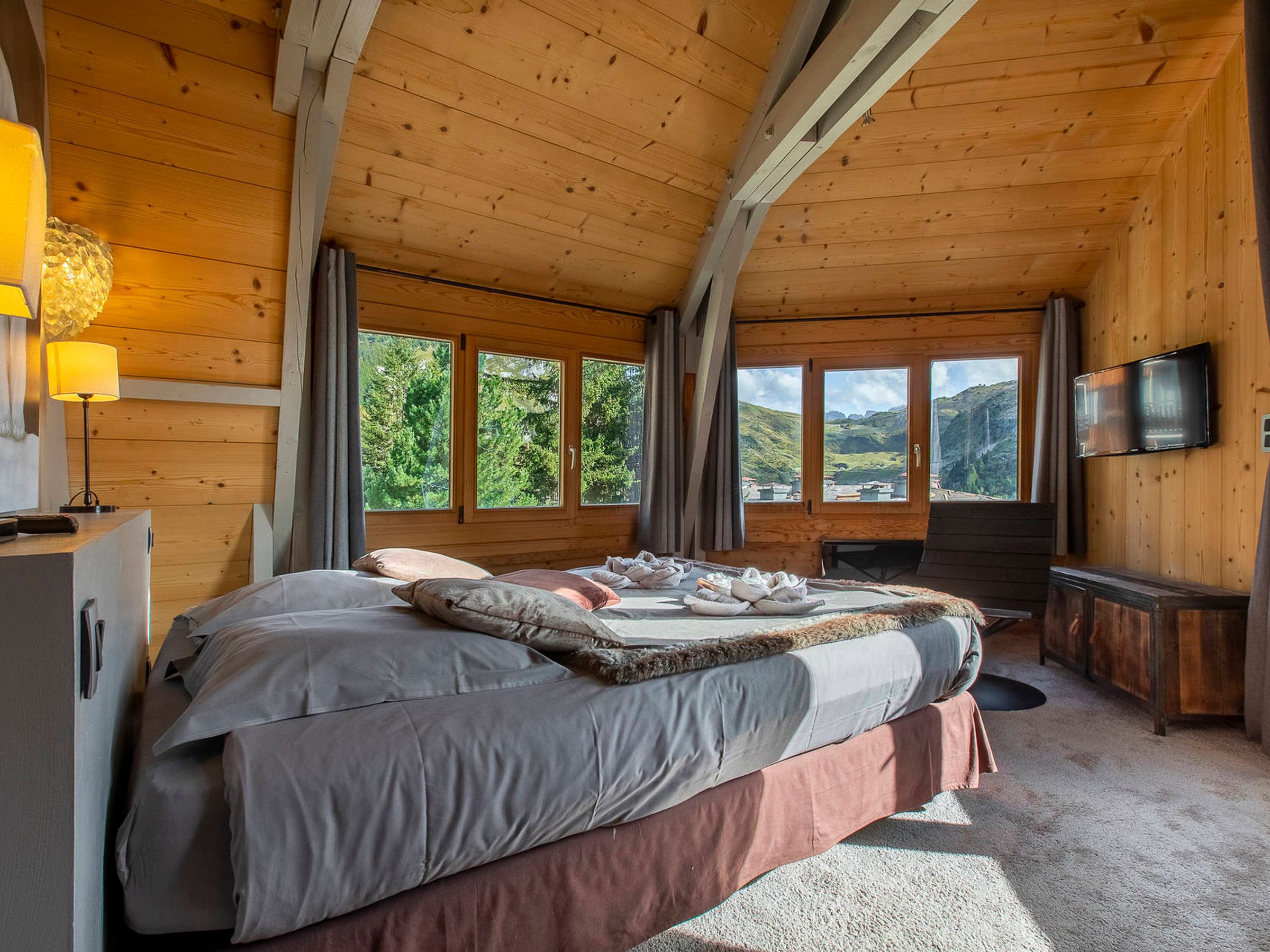 Une chambre confortable dans un chalet en bois, avec un lit, un bureau et un téléviseur.