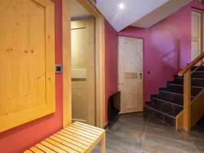 Eine Holzbank, eine Treppe und eine Tür in einem Raum mit roter Wand.
