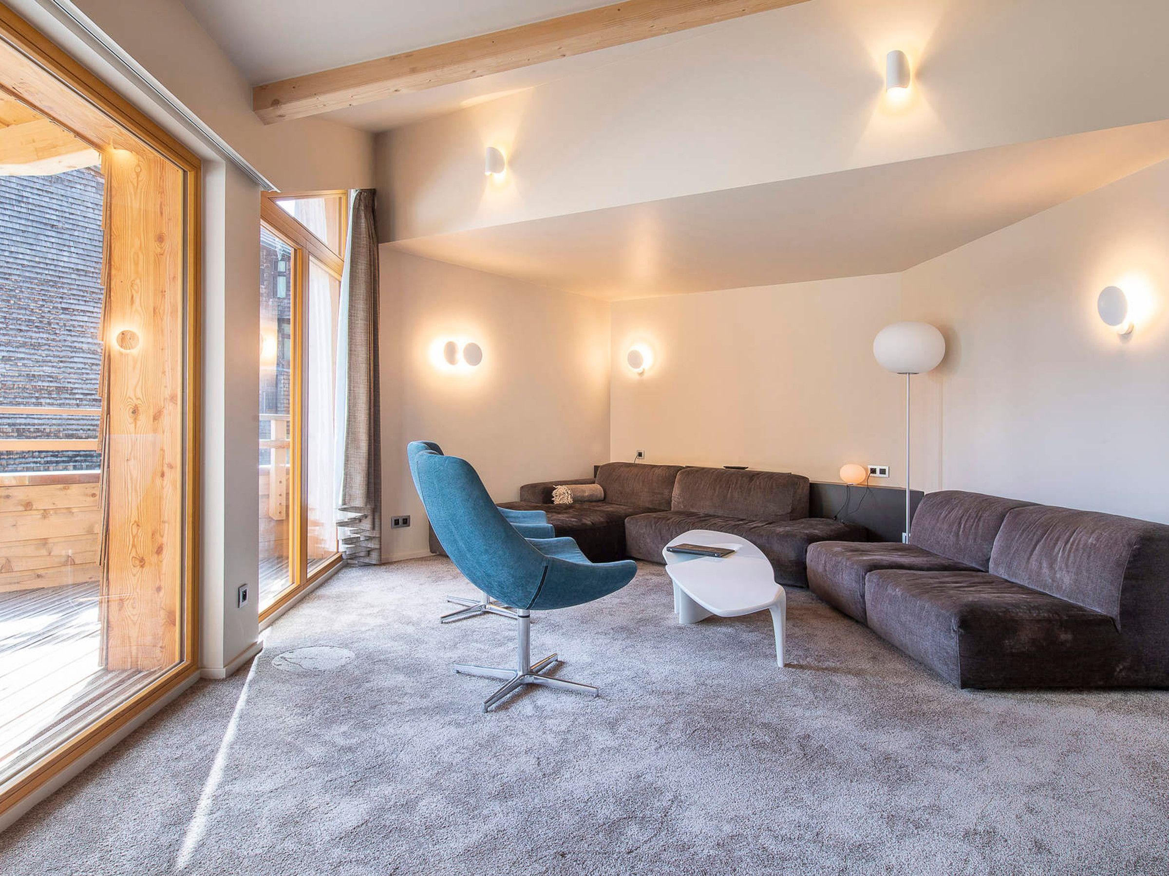 Ein modernes Wohnzimmer mit einer Eckcouch, einem blauen Sessel und einem kleinen weißen Tisch.
