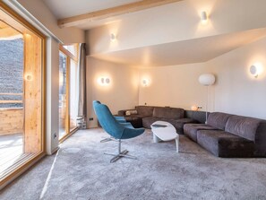 A modern living room with a sectional sofa, a blue chair, and a small white table. - Exceptional chalet, central location - 10 guests (Avoriaz)