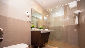 Un baño moderno con cabina de ducha de vidrio, tocador de tonos oscuros y un inodoro.