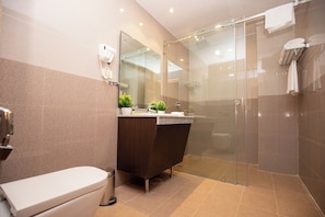 Un baño moderno con cabina de ducha de vidrio, tocador de tonos oscuros y un inodoro.