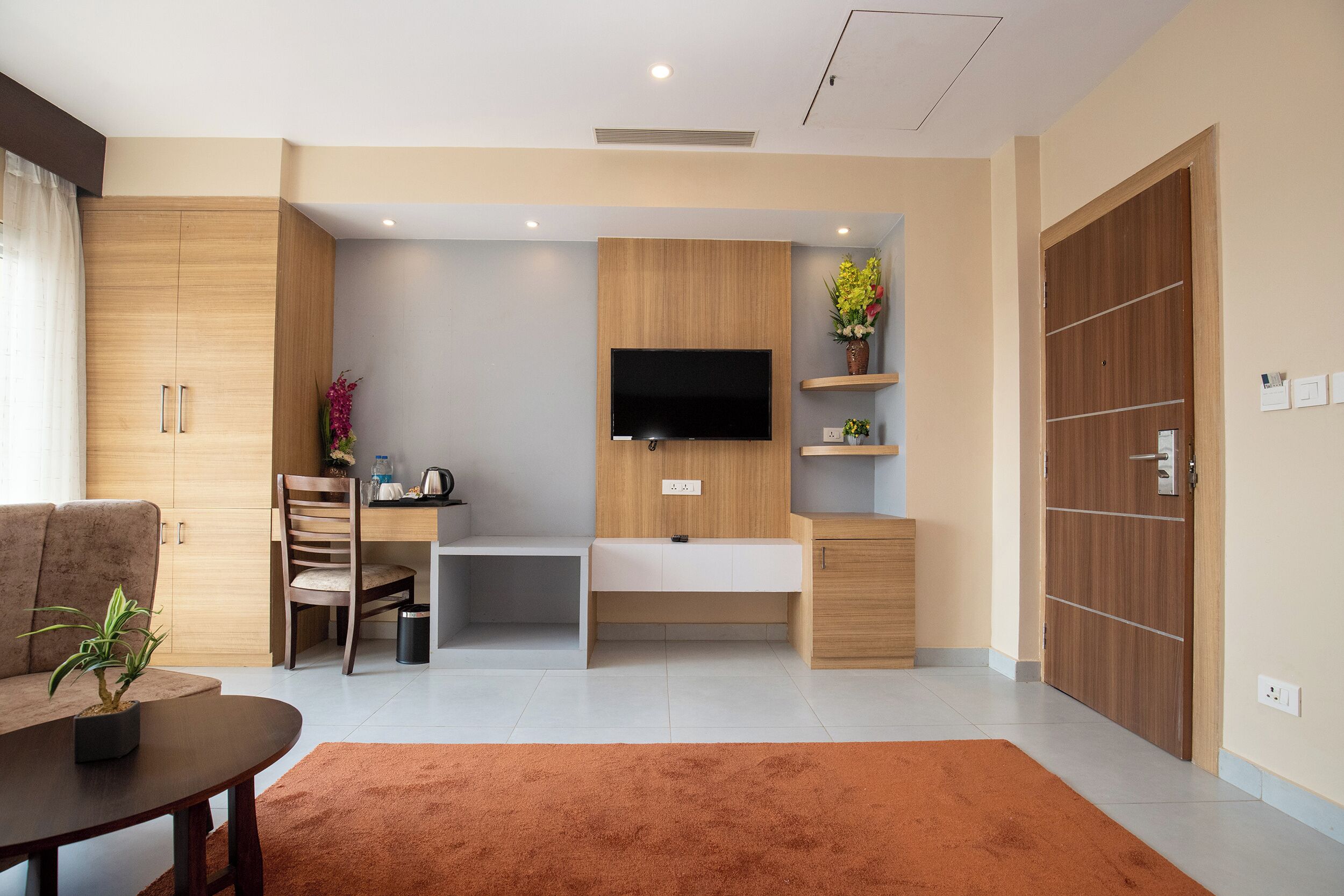 Una sala de estar moderna con un sofá, una mesa de centro, un televisor montado en una pared de madera y un escritorio pequeño con una silla.