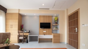 Una sala de estar moderna con un sofá, una mesa de centro, un televisor montado en una pared de madera y un escritorio pequeño con una silla.