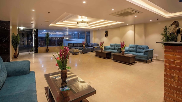 Un vestíbulo amplio con una lámpara moderna, zona de estar con sofás y sillones, y un ventanal con vistas al exterior.
