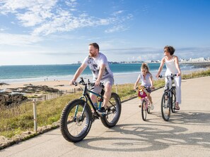 Three people riding bicycles on a paved path by the beach. - Comfortable apartment near the beach - 5 guests (Les Sables-d'Olonne)