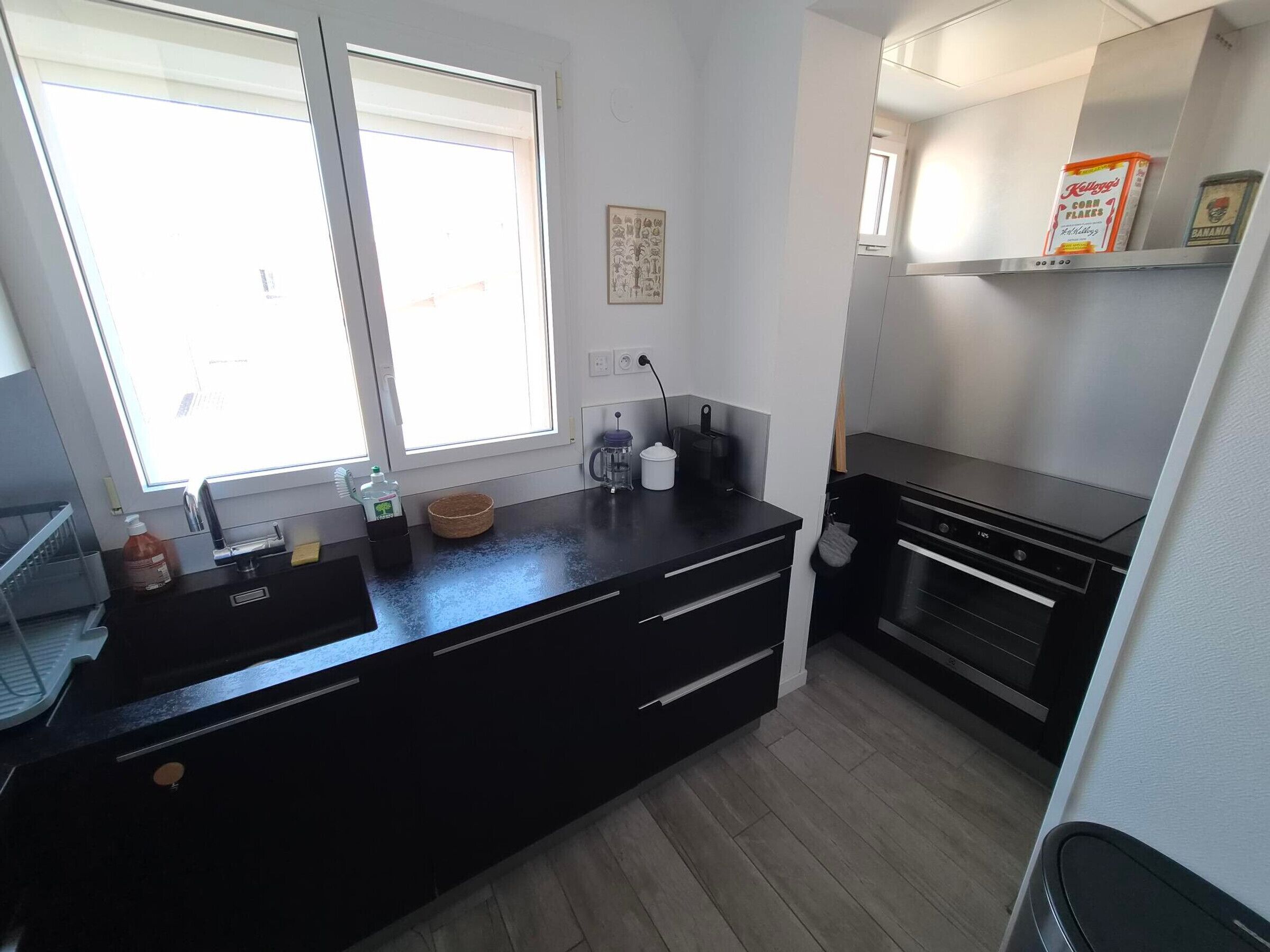 A modern kitchen with a black countertop, stainless steel appliances, and a window providing natural light.