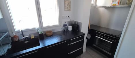 A modern kitchen with a black countertop, stainless steel appliances, and a window providing natural light.
