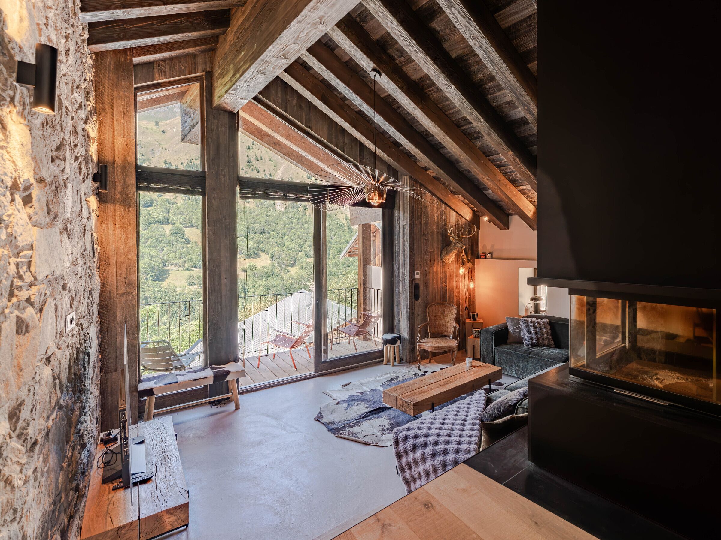 Ein geräumiger Raum mit großem Fenster, Kamin und rustikaler Steinwand.