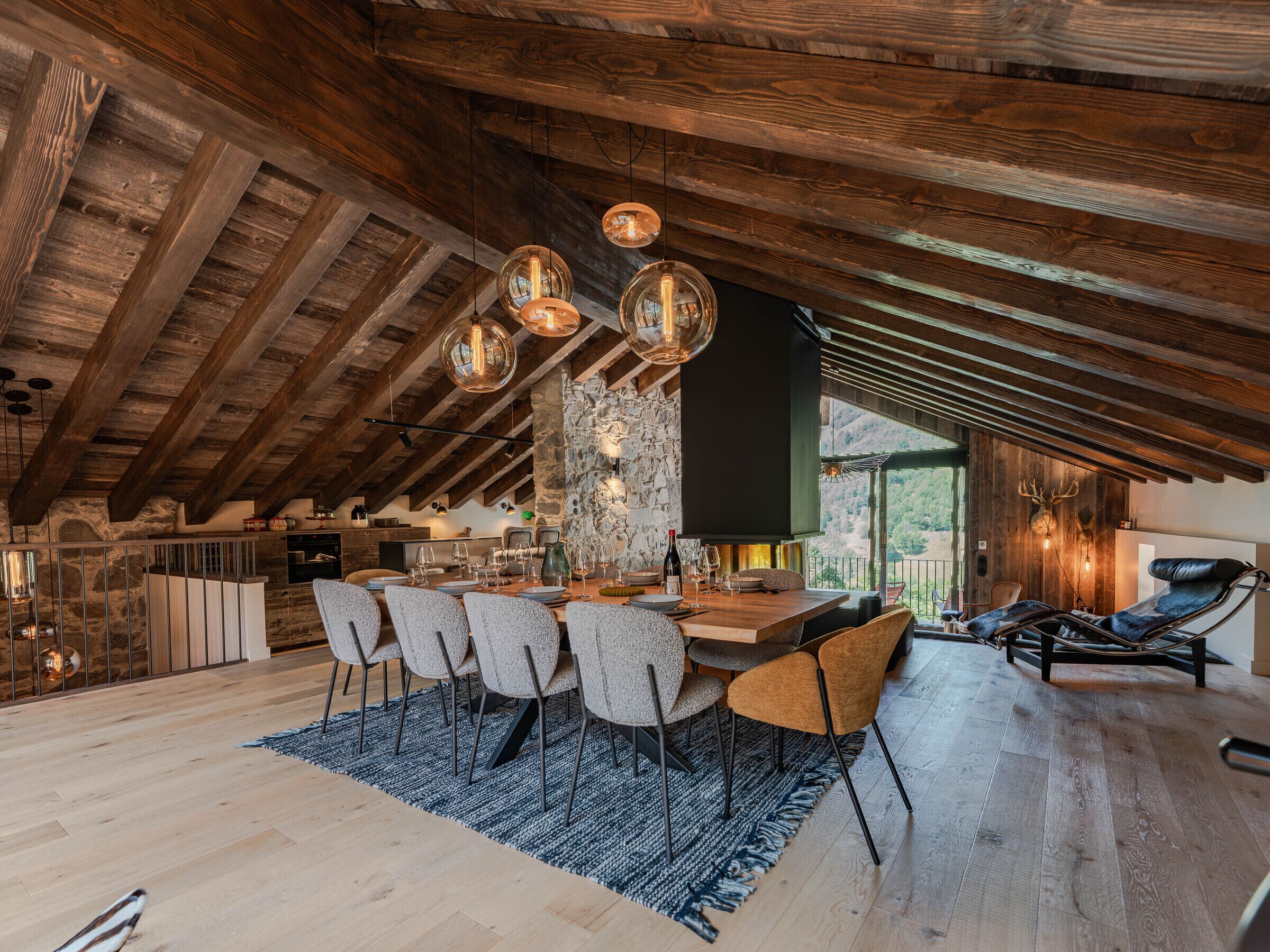 Comedor con techo de madera, pared de piedra y vistas al exterior.