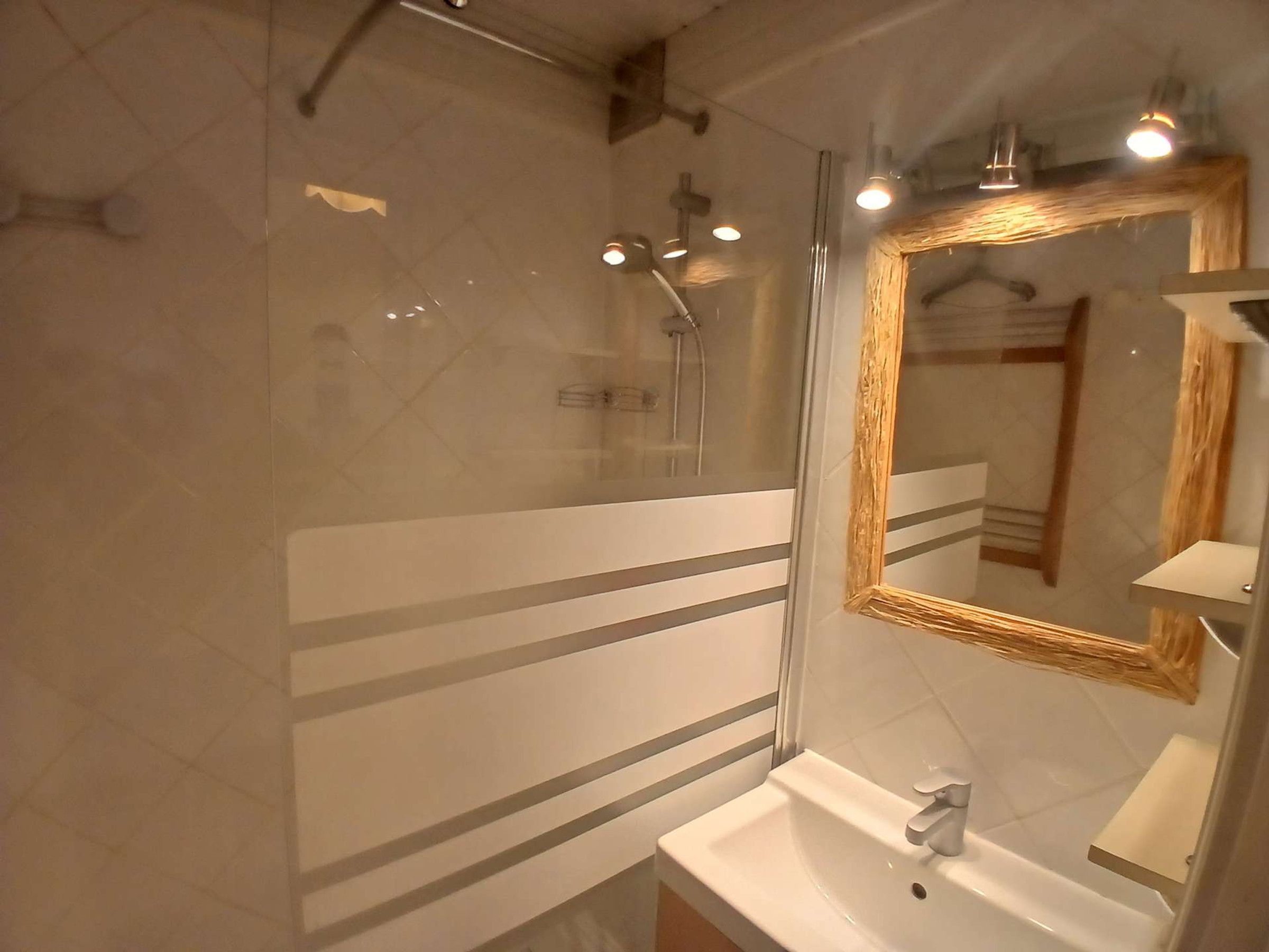 A bathroom with a glass shower enclosure, a sink with a mirror, and a towel rack.