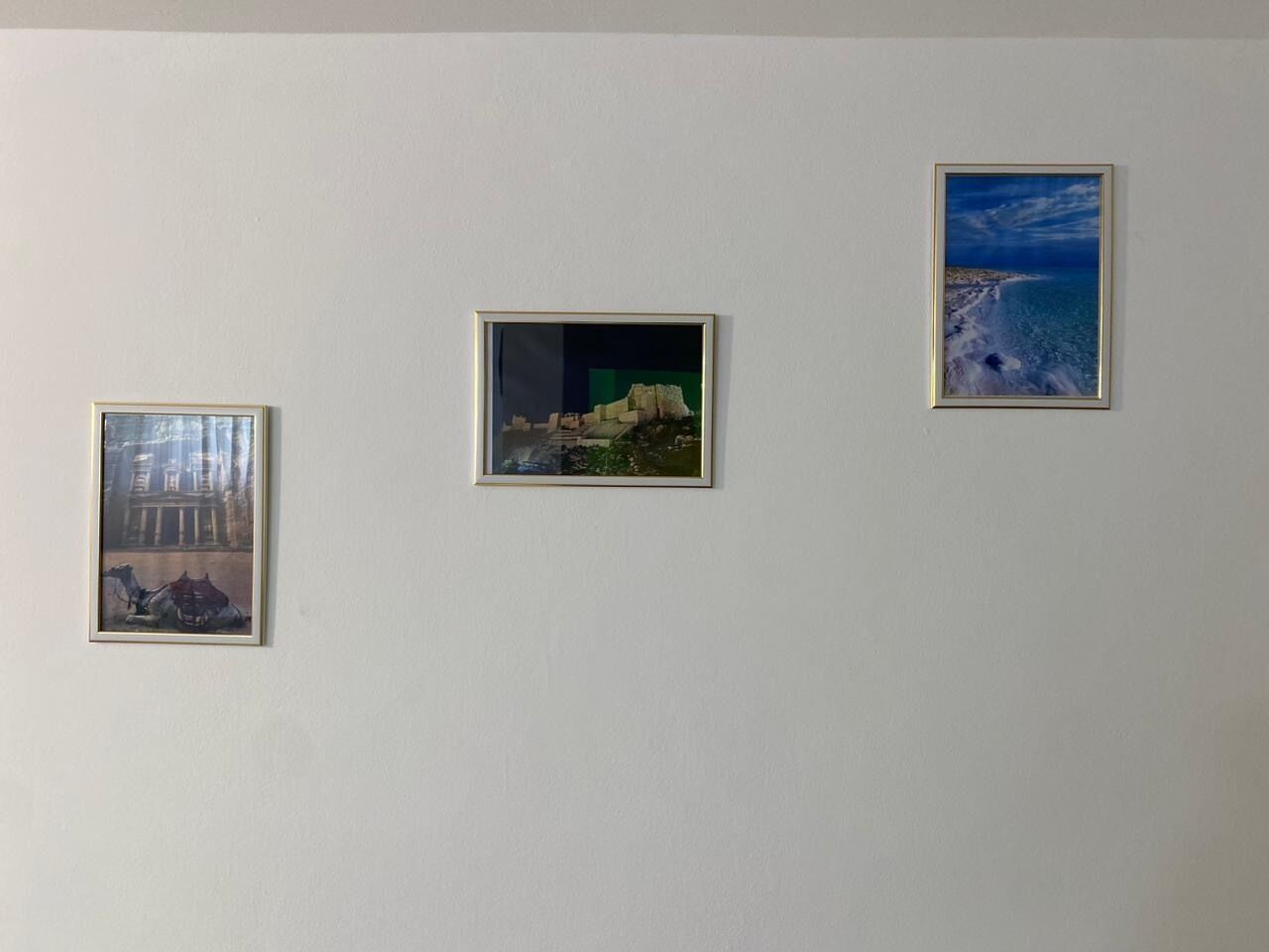 Drei gerahmte Kunstwerke an einer schlichten Wand.