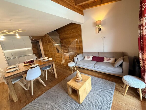 Un salon confortable avec une table à manger, un canapé et un escalier menant à l’étage supérieur.