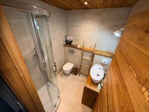 Une salle de bain avec une douche à parois de verre, des toilettes, un lavabo et un meuble-lavabo en bois.