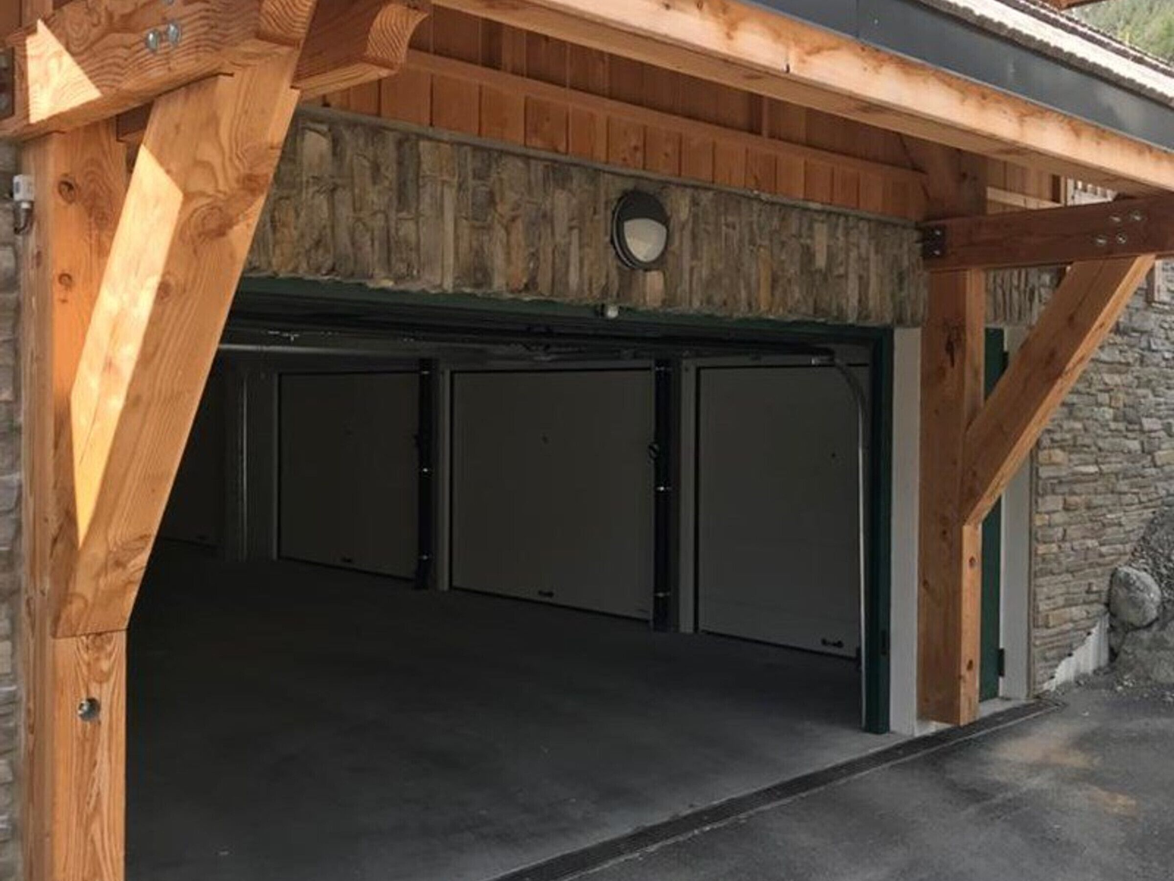 Uma garagem com estrutura de madeira e parede de pedra.