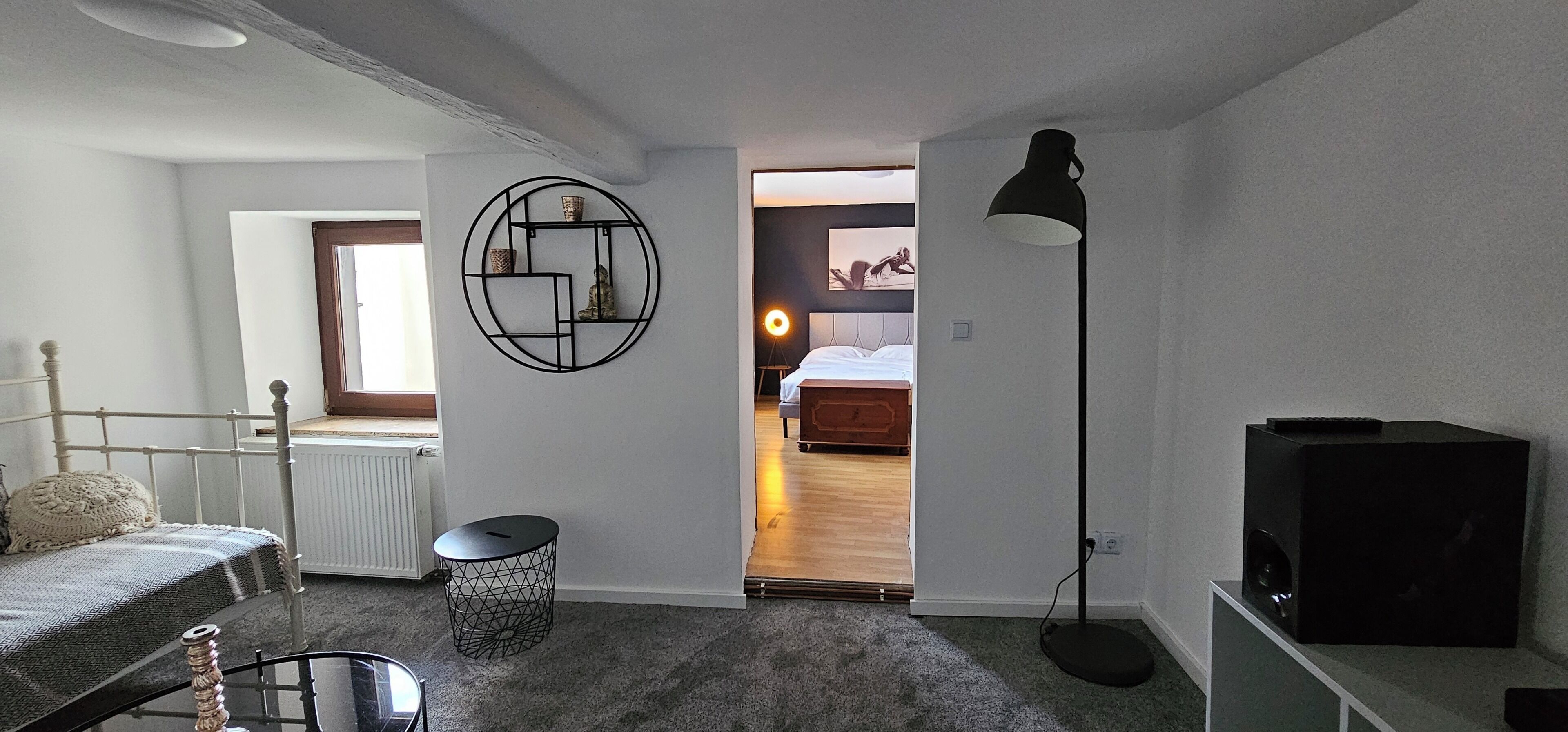 Een slaapkamer met een bed, nachtkastje, lamp, radiator en raam.