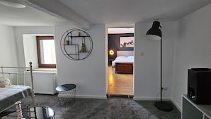 A bedroom with a bed, a bedside table, a lamp, a radiator, and a window.