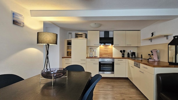 A compact kitchen with a dining table, chairs, a lamp, and modern appliances.