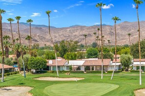 Un parcours de golf offrant une vue dégagée sur le paysage environnant, notamment sur les montagnes et les immeubles résidentiels.