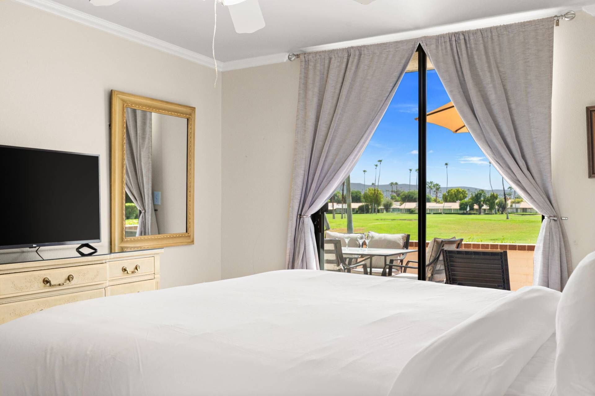 Una camera d'hotel con un letto, una televisione, un comodino e vista su un campo da golf.