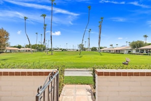 A golf course with a clear sky, palm trees, and a brick pathway leading to a building. - Rancho Mirage Vacation Condo | Panoramic Triple Fairway Views | Rancho Las Palmas Country Club (Rancho Mirage)