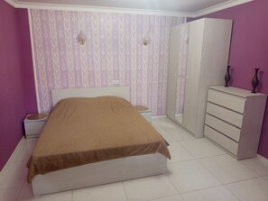 Une chambre à coucher comprenant un lit, une armoire, une table de chevet et un miroir.