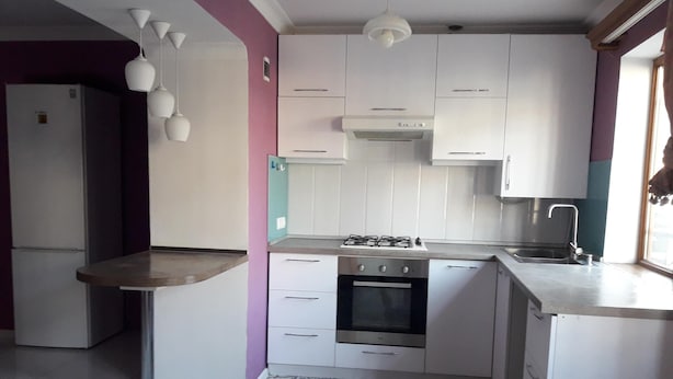 Cocina con armarios blancos, estufa a gas, horno integrado, pileta de acero inoxidable y pisos con diseños.