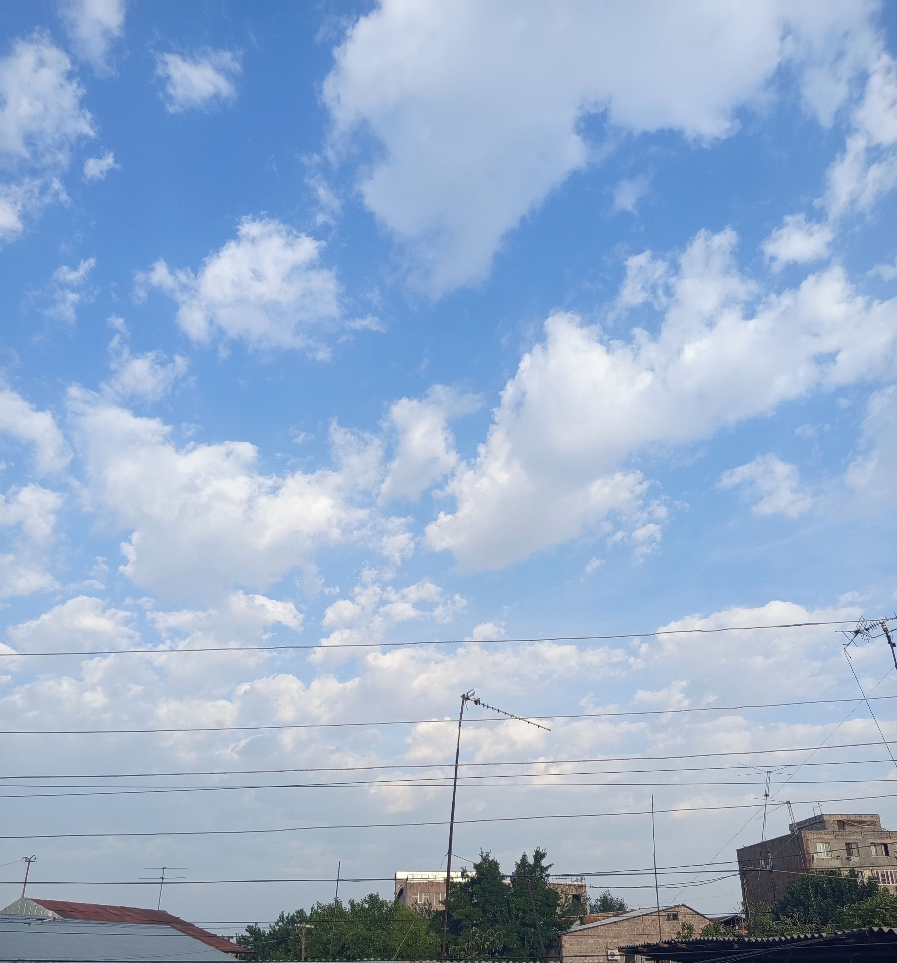 Cielo sereno con nuvole sparse e linee elettriche.