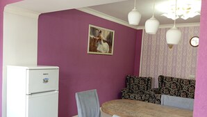 Comedor con mesa y sillas, refrigerador, papel tapiz estampado y una araña.