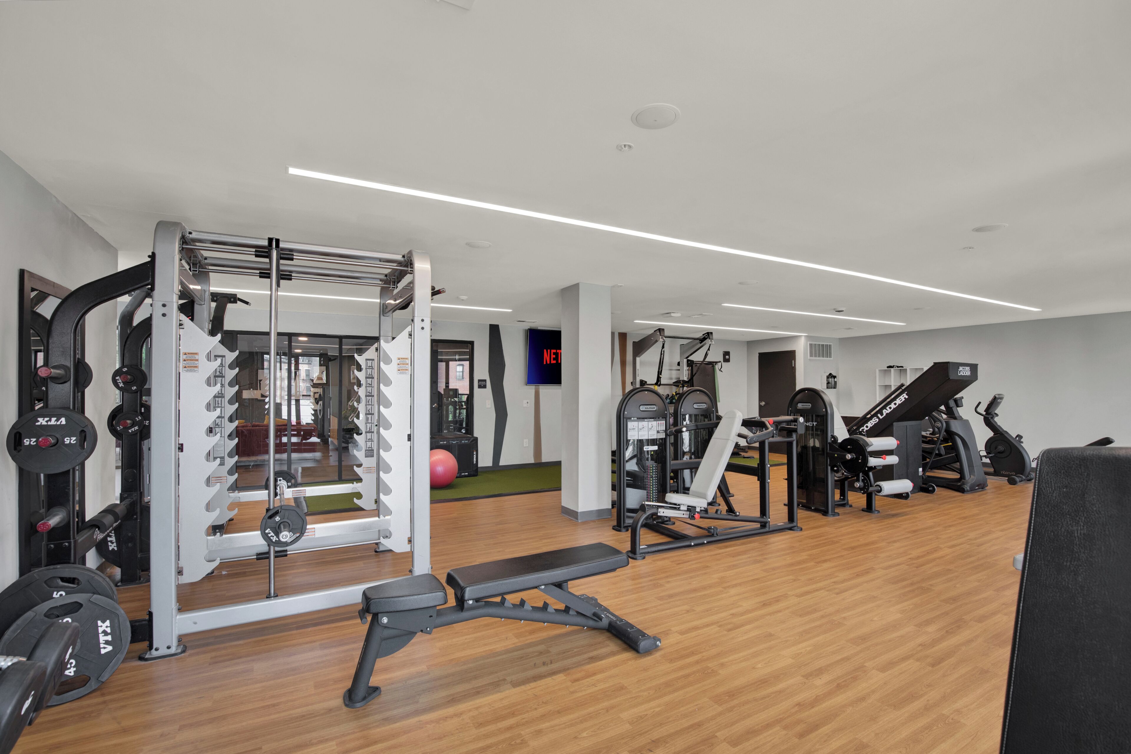 Een moderne sportschool met diverse fitnessapparaten, waaronder een squatsrek en krachttoestellen.