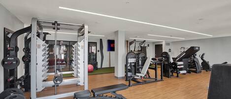 Un gimnasio moderno con diverso equipo de ejercicio, incluyendo una estructura para sentadillas y máquinas de pesas.