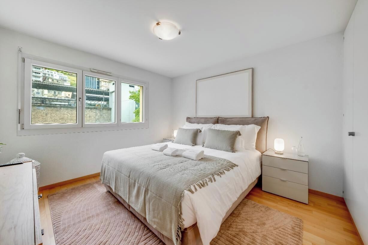 Ein Schlafzimmer mit Bett, Nachttisch und einem Fenster mit Blick.