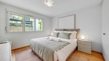 Ein Schlafzimmer mit Bett, Nachttisch und einem Fenster mit Blick.