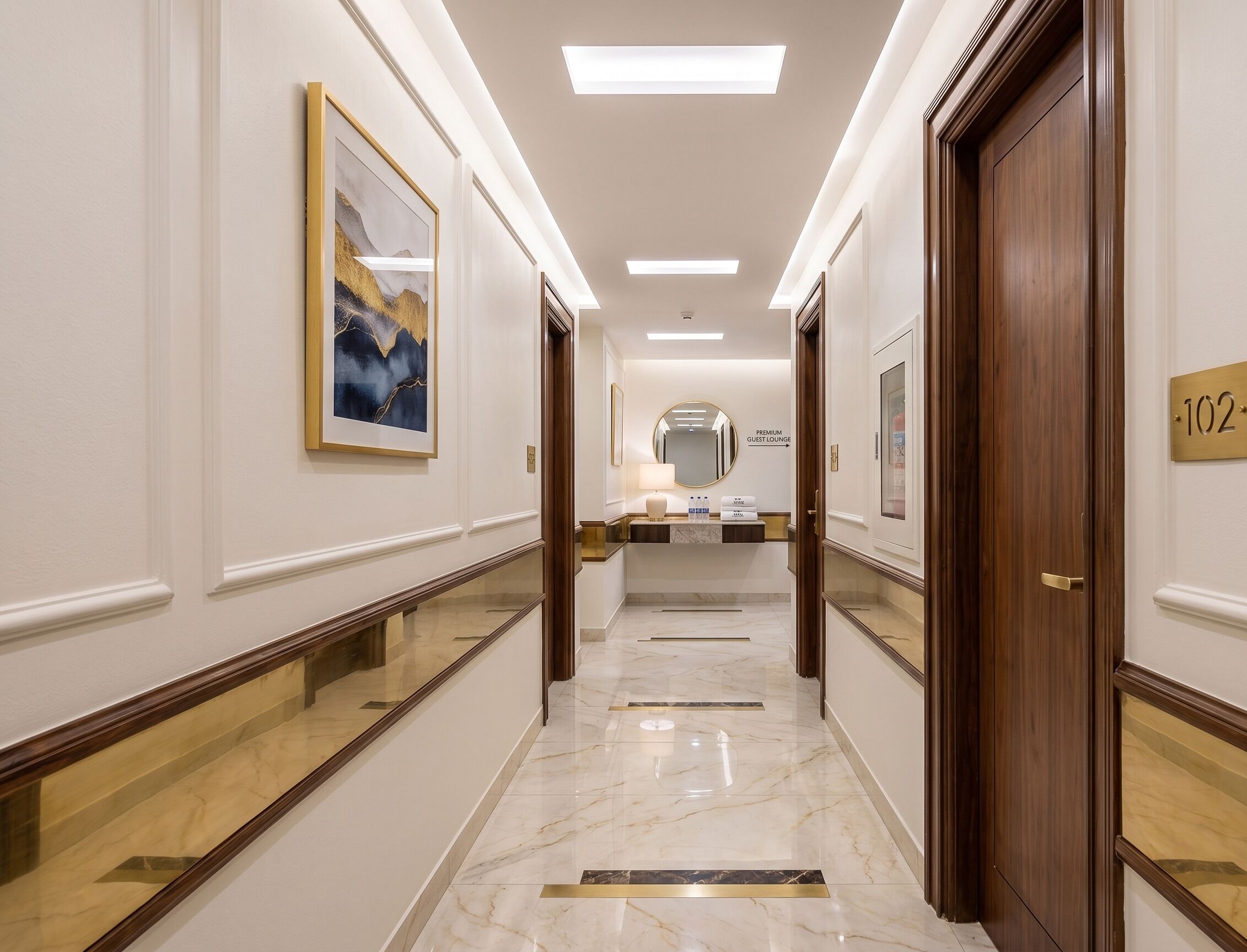 A hotel corridor with a marble floor, framed artwork, and a sign indicating a guest lounge.