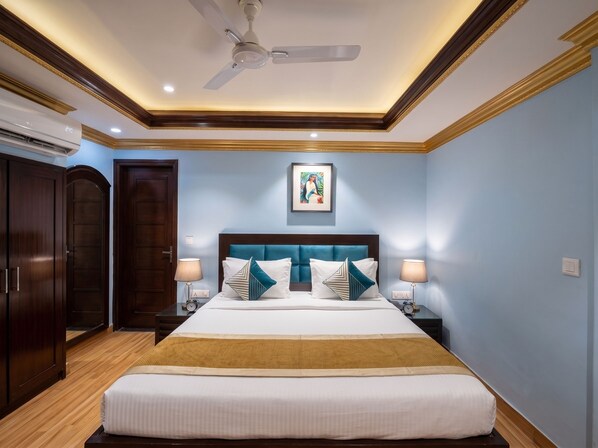 Una habitación de hotel con cama, mesitas de noche, ventilador de techo y un cuadro en la pared.