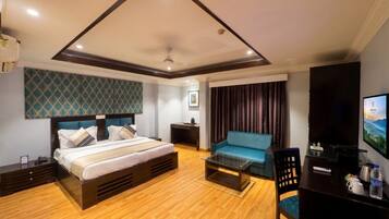 A hotel room with a bed, a sofa, a TV, and a desk with a chair.