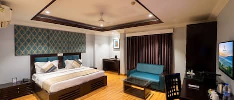 Una habitación de hotel con una cama, un sofá, un televisor y un escritorio con una silla.