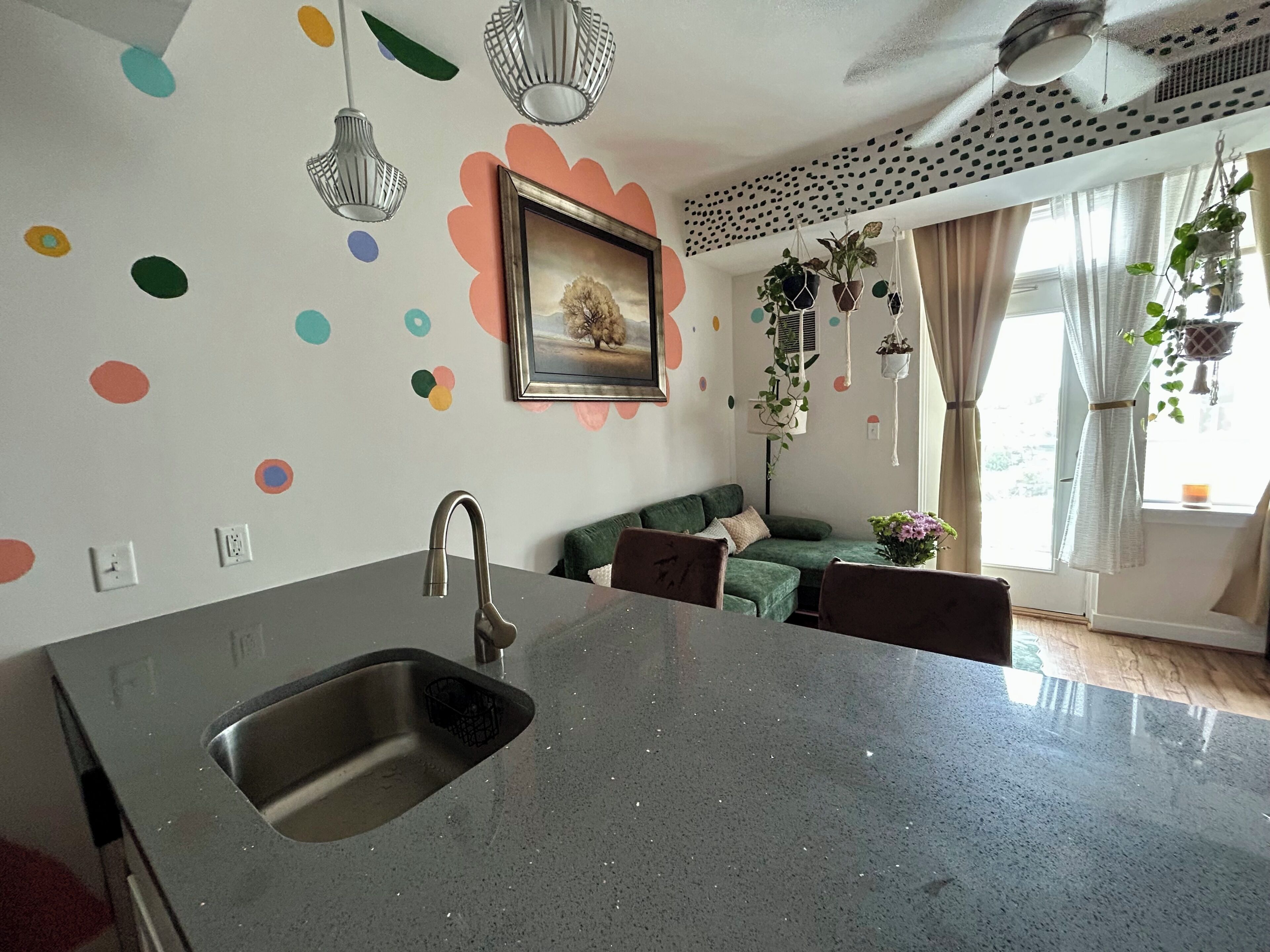 Una cucina con un lavello in acciaio inox, un divano verde e una ventola a soffitto.