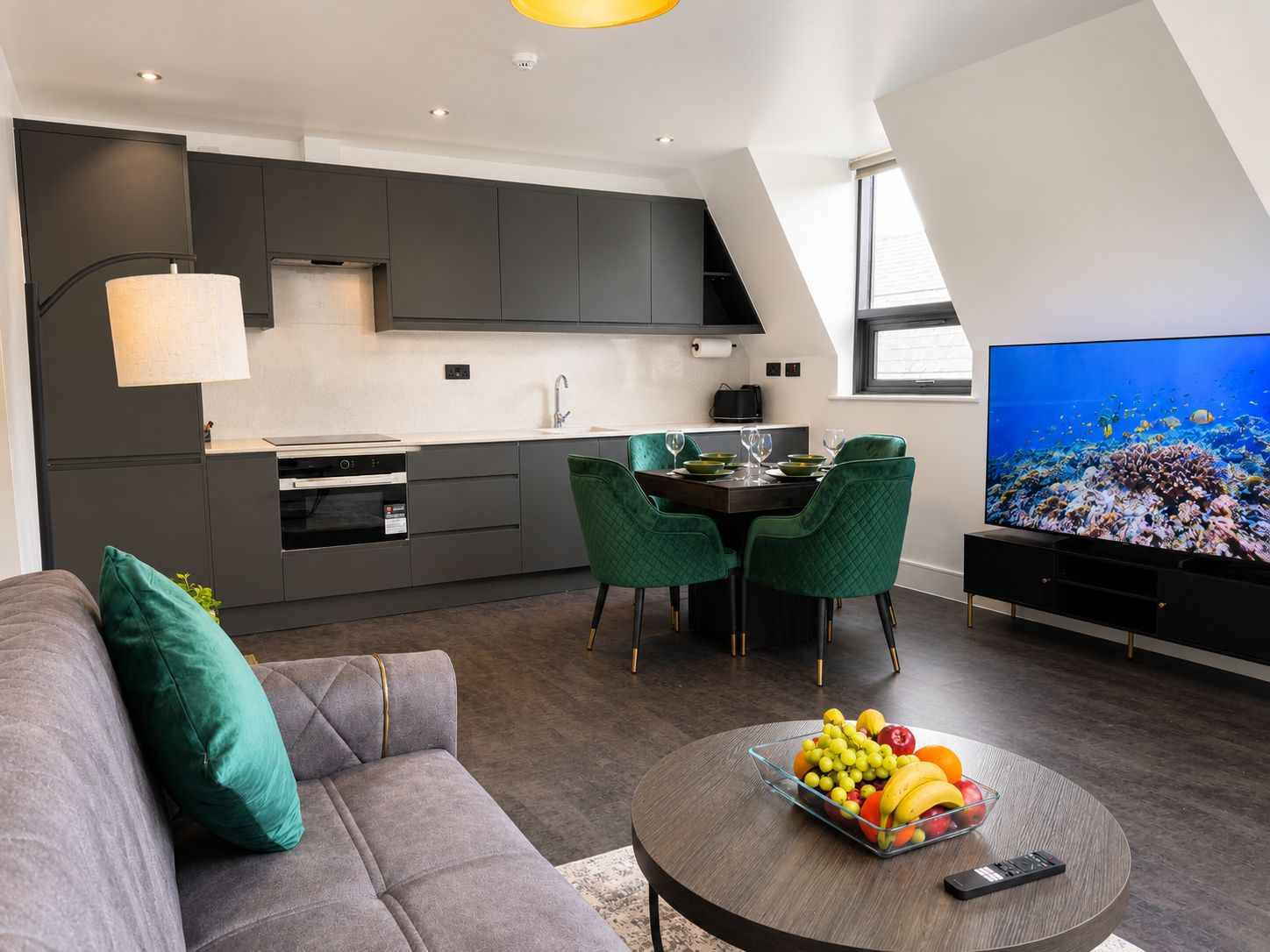 Um espaço moderno para viver, com área de refeições, cozinha e uma televisão de tela plana grande.