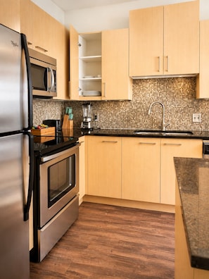 A modern kitchen with stainless steel appliances, wooden cabinets, a tiled backsplash, and a granite countertop. - 3 Queen bed downtown Dallas gym&pool (Dallas)