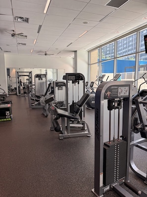 A gym with various exercise machines, a large mirror, and a window with a view of the outside. - 3 Queen bed downtown Dallas gym&pool (Dallas)