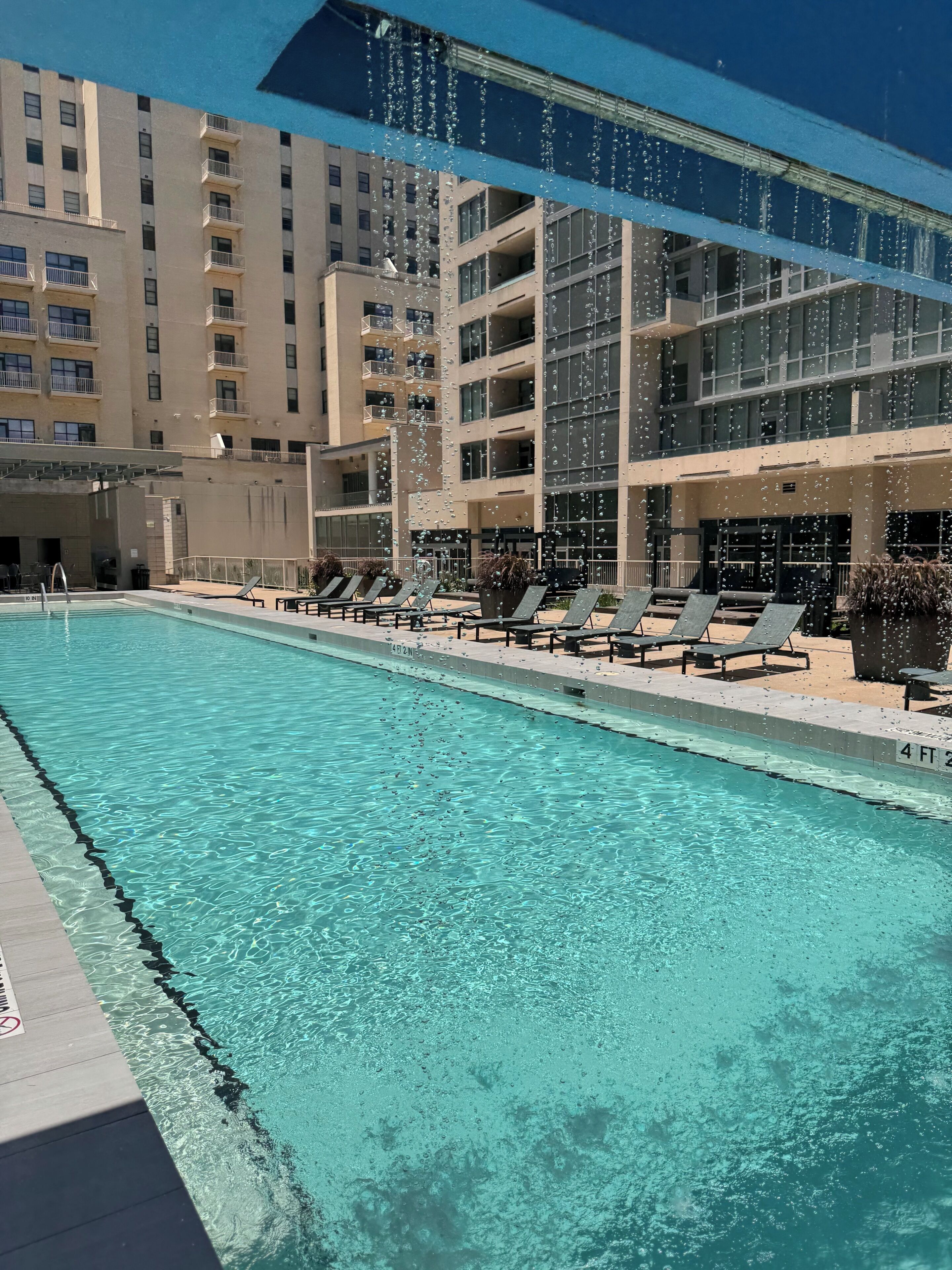 A swimming pool with lounge chairs and a building in the background.