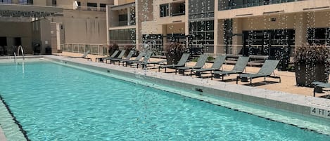 A swimming pool with lounge chairs and a building in the background.