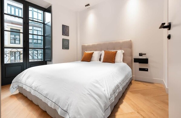 A bedroom with a bed, a window with a view, and a bedside table. - High-end apartment in the centre,3m from the beach (Gijón)