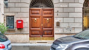 A double wooden door with a metal fanlight above it, a red mailbox, and a sign indicating the property is a condominium.