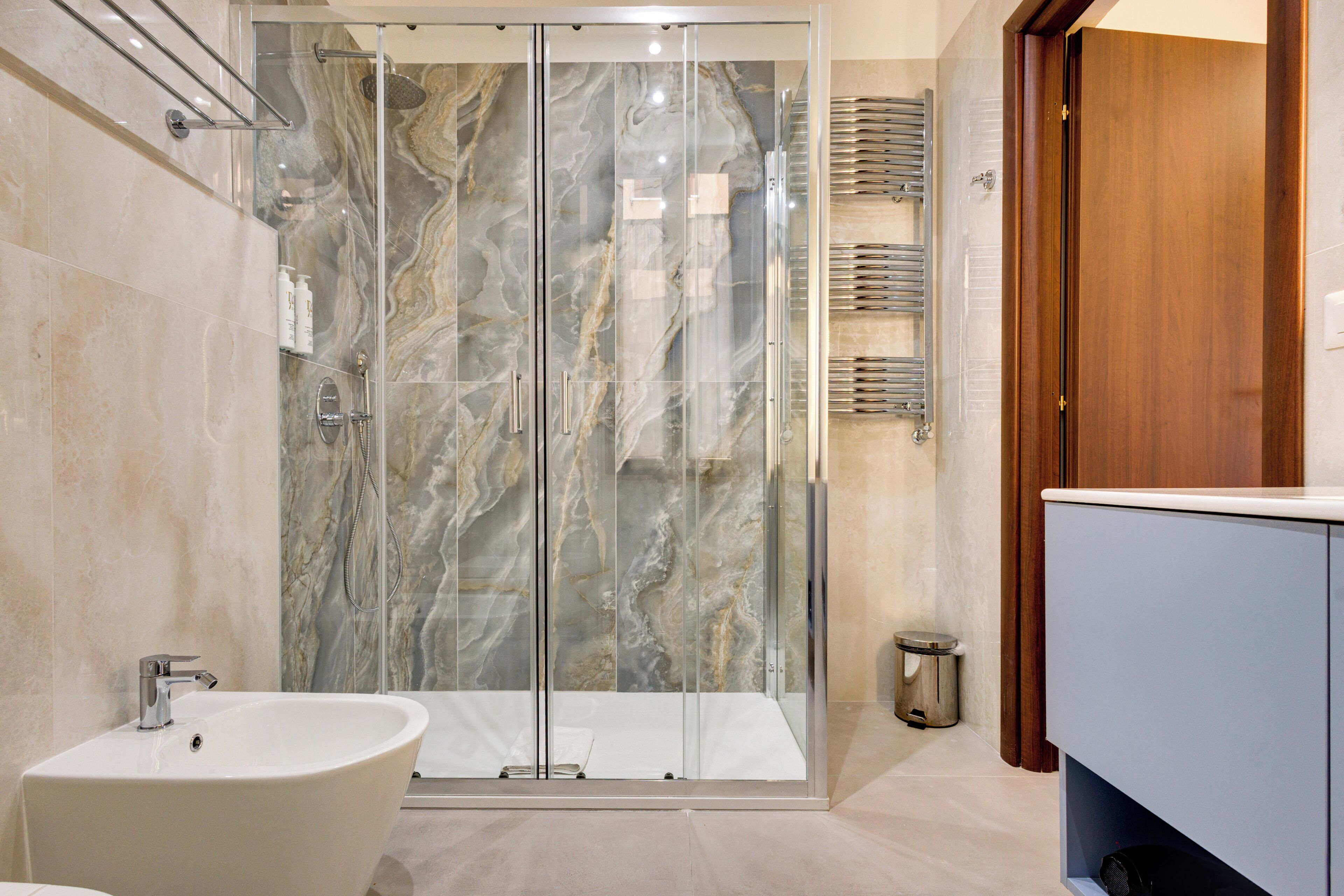 Un baño moderno con cabina de ducha de vidrio, lavabo blanco y tocador de madera.