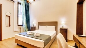 A hotel room with a bed, bedside lamps, a wooden desk, and a chair.